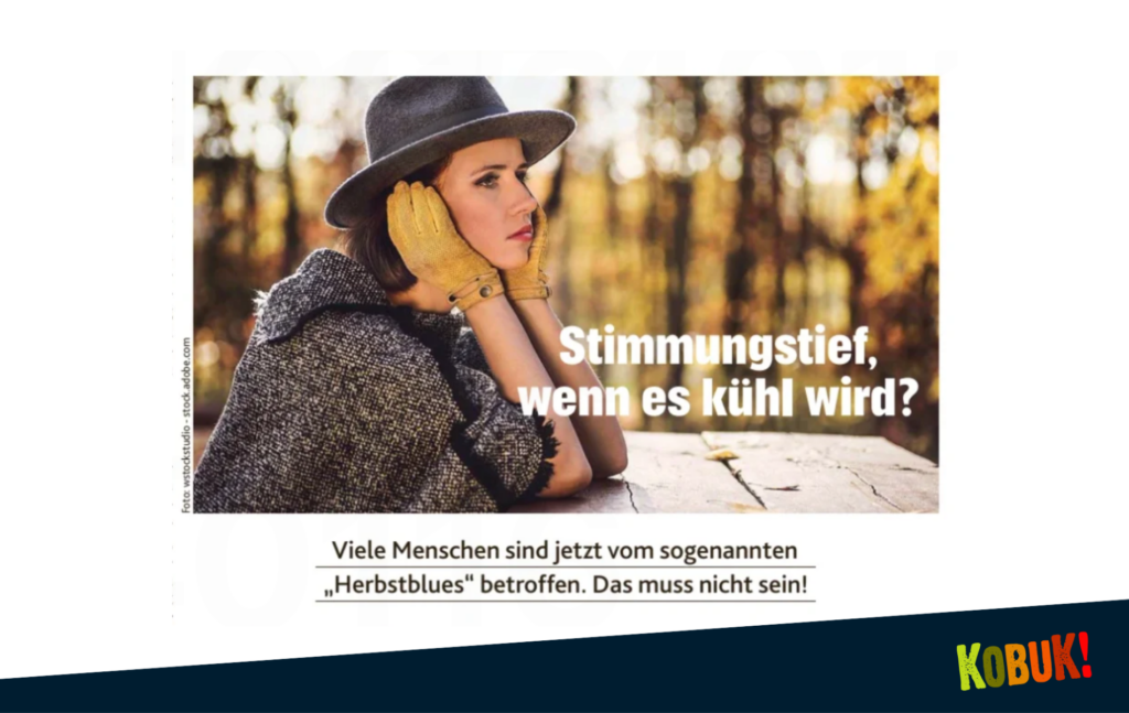 Eine traurig aussehende Frau mit Hut, Poncho und Handschuhen, im Hintergrund gelb-brauner Herbstwald. Dieses Bild soll ein Stimmungstief im Herbst illsutrieren. 